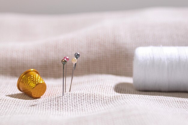 Zestaw nici i igieł na tle materiału